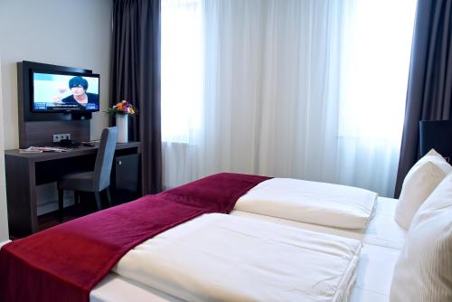 Dormitorio con cama, escritorio y TV en Milbor Hotel en Bad Soden am Taunus