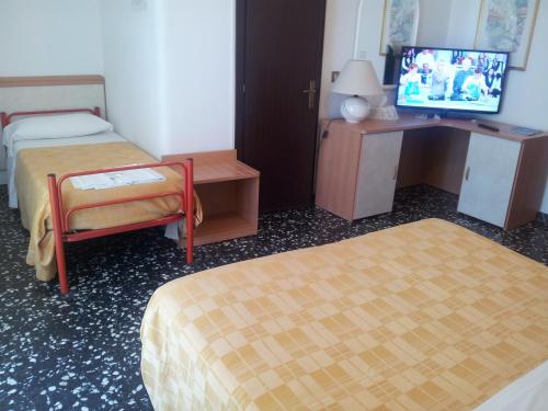 a hotel room with two beds and a desk and a tv at Hotel Rosa Meublé in Porto San Giorgio