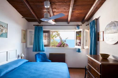 a bedroom with a blue bed and a window at Villa Tonnara in San Vito lo Capo