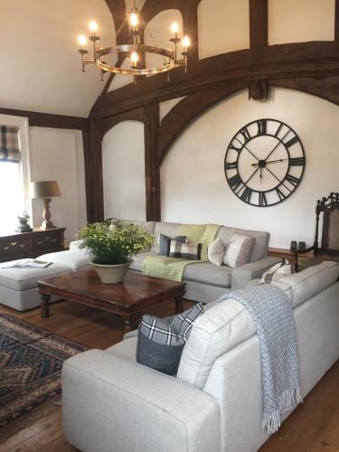 a living room with a large clock on the wall at White Hall Farm in Leamington Spa