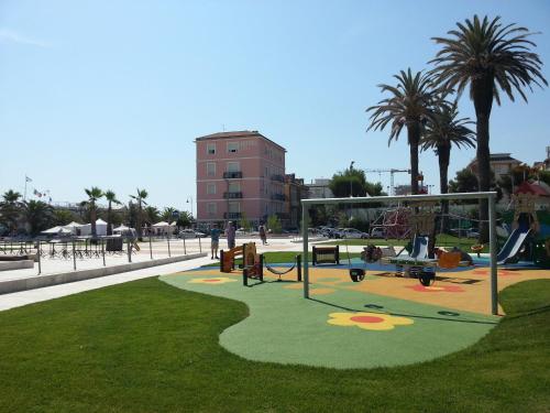 a park with playground equipment and palm trees at Hotel Rosa Meublé in Porto San Giorgio