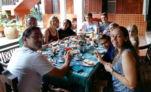 eine Gruppe von Menschen sitzt um einen Tisch herum und isst in der Unterkunft Golden Teak Home Resort in Saraphi