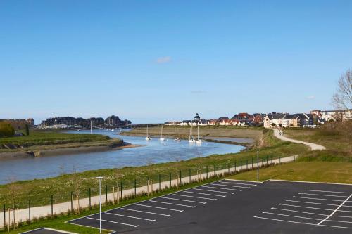 a parking lot next to a river with boats in it at Kyriad Prestige Residence & Spa Cabourg-Dives-sur-Mer in Dives-sur-Mer