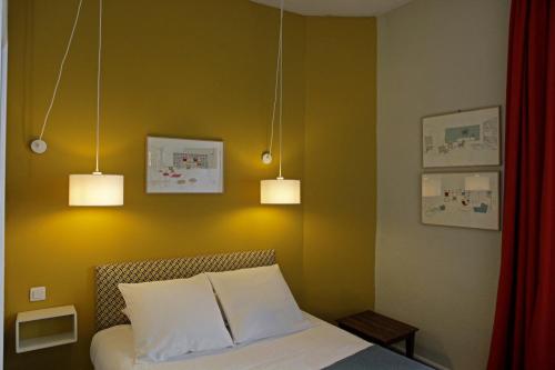a bedroom with a bed with three lights above it at Hotel Auberge des Remparts in Laval
