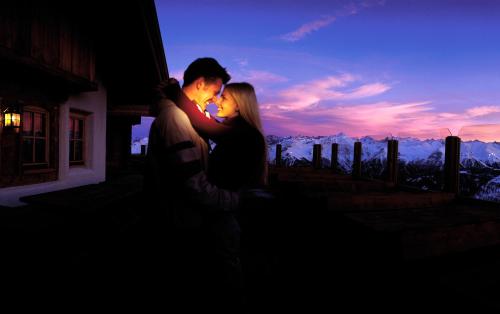 a man and a woman standing in front of a sunset at Haus Central in Serfaus