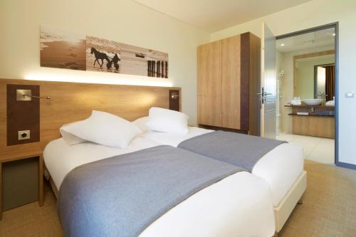 a bedroom with a large bed and a bathroom at Kyriad Prestige Residence & Spa Cabourg-Dives-sur-Mer in Dives-sur-Mer
