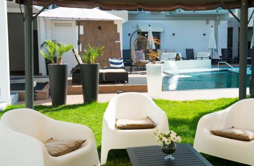 a patio with white chairs and a table and a pool at Hotel Rossini 4S in Lignano Sabbiadoro