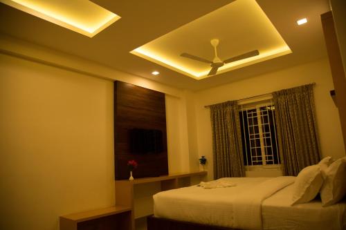 a bedroom with a ceiling fan and a window at Hotel Grand Tree in Coimbatore