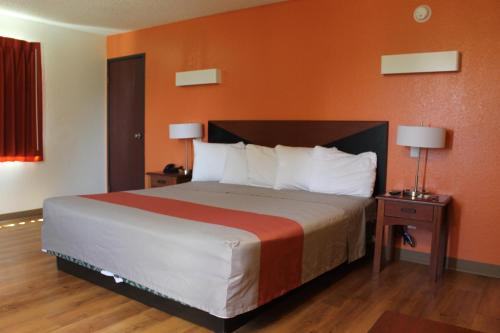 ein Schlafzimmer mit einem großen Bett mit orangefarbenen Wänden in der Unterkunft Ashley Inn Ponca City in Ponca City