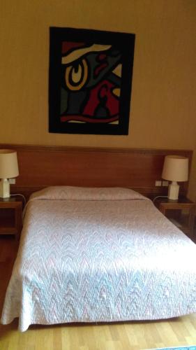 a bedroom with a bed with two lamps and a painting at Hotel de l'Orangerie in Strasbourg