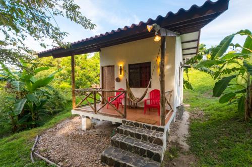 a tiny house with a porch and a red chair at Istmo Beach and Jungle Bungalows in San Carlos