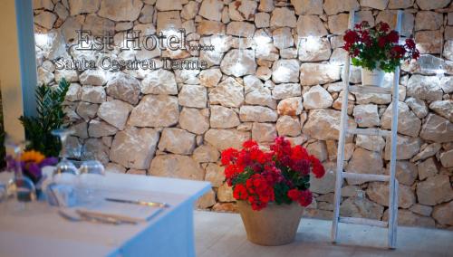 a room with a stone wall with flowers in a vase at Est hotel in Santa Cesarea Terme