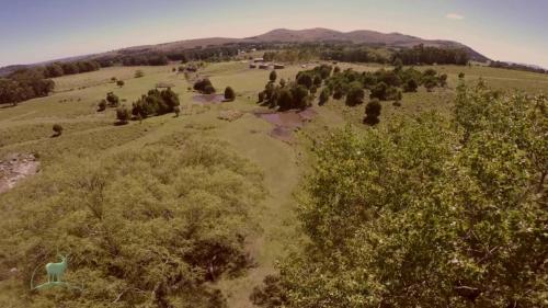 an aerial view of a field with trees and houses at Cabañas Valle de los Ciervos in Tandil