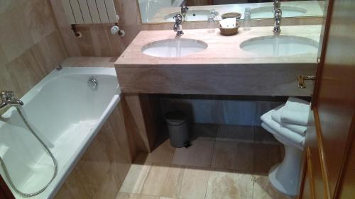 a bathroom with two sinks and a bath tub at Hotel de l'Orangerie in Strasbourg