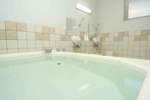 a bath tub in a bathroom with a shower at Pension Ashitaya in Furano