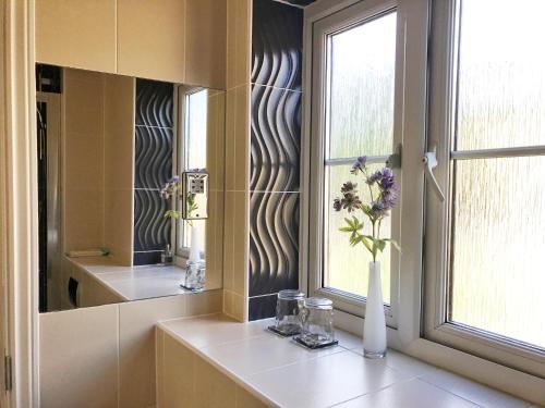 a bathroom with a window and a vase with flowers at Moon House in Oxford