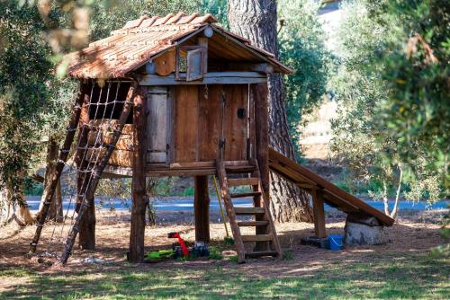 a tree house with a ladder and a swing at Agriturismo Fontetrilla in Orbetello