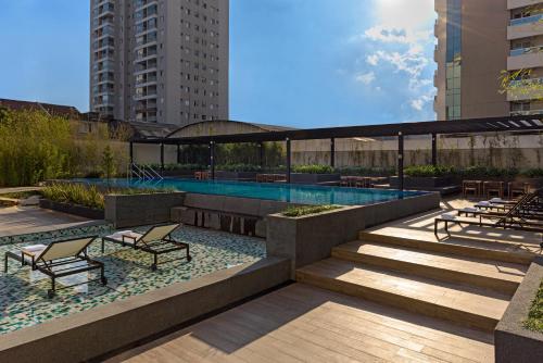 a patio with a swimming pool and stairs and chairs at Aparthotel Adagio Sao Paulo Barra Funda in São Paulo