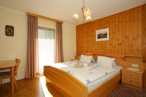 ein Schlafzimmer mit einem Bett mit einer Holzwand in der Unterkunft Familienparadies Zeislerhof in Glanegg