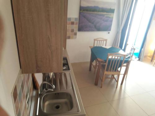uma cozinha com um lavatório e uma mesa com cadeiras em Il Faro em Acquappesa