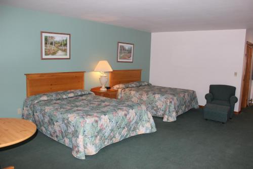a hotel room with two beds and a chair at Nootka Lodge in Woodsville