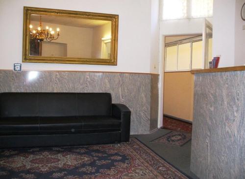 a living room with a black couch and a mirror at Hotel Messe am Funkturm in Berlin