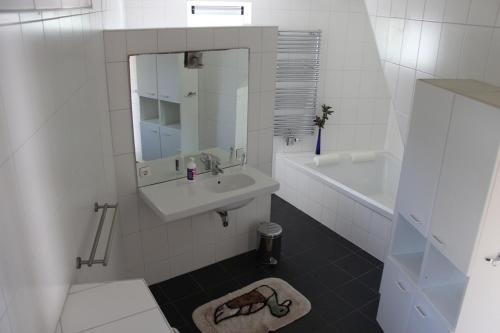 a white bathroom with a sink and a mirror at TS37 in West-Terschelling