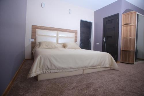 a bedroom with a large white bed with a wooden headboard at Evim Otel in Zaqatala