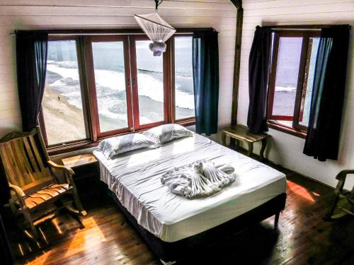a bedroom with a bed with a view of the ocean at Magnific Rock - Surf Resort & Yoga Retreat Nicaragua in Popoyo