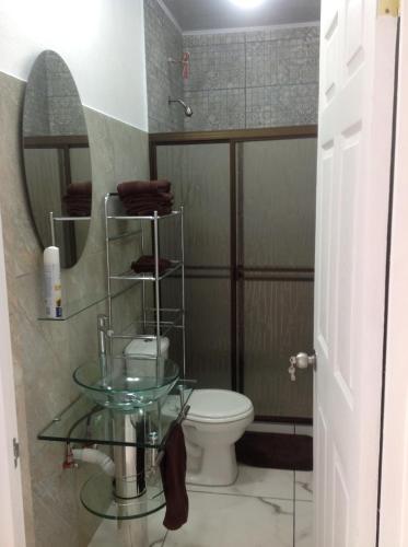 a bathroom with a toilet and a glass table at Punta Leona Beach Condos in Jacó