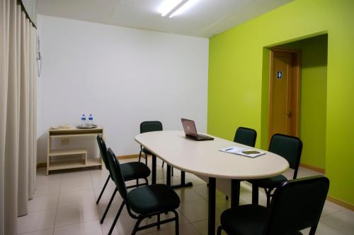 a room with a table with chairs and a laptop on it at Hotel Jardim Europa in Ijuí