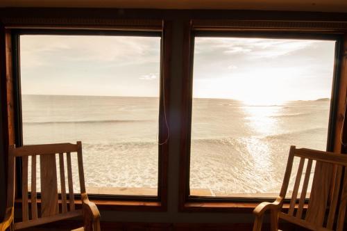 a window with two chairs looking out at the ocean at Magnific Rock - Surf Resort & Yoga Retreat Nicaragua in Popoyo