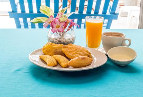 einen Teller mit Gebäck und eine Tasse Kaffee und Orangensaft in der Unterkunft Hotel Altamar Cartagena in Cartagena de Indias