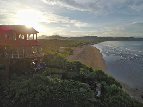 a house on a hill next to a beach at Magnific Rock - Surf Resort & Yoga Retreat Nicaragua in Popoyo