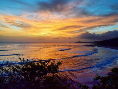 a sunset on a beach with the ocean at Magnific Rock - Surf Resort & Yoga Retreat Nicaragua in Popoyo