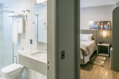 a bathroom with a bed and a toilet and a sink at Tri Hotel Premium Criciúma in Criciúma