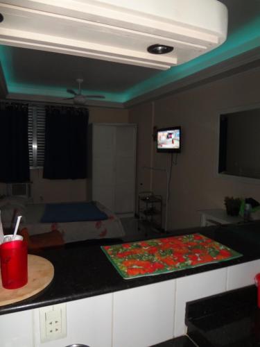 Habitación con cocina con mesa y TV. en Apartamento da Marlene, en Río de Janeiro