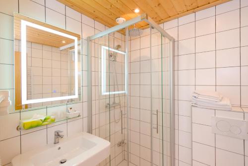 a white bathroom with a shower and a sink at Landhotel Groggerhof in Obdach