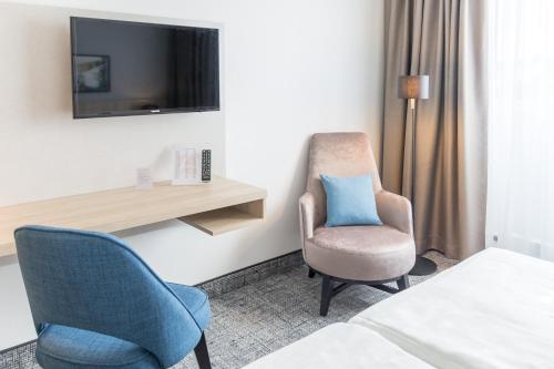a hotel room with a chair and a tv at Ramada by Wyndham Flensburg City in Flensburg