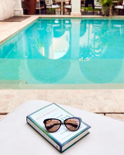 a book with glasses sitting on a table next to a pool at Casa Lecanda Boutique Hotel in Mérida
