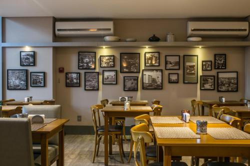 クリシウマにあるTri Hotel Premium Criciúmaの壁に絵画が飾られたテーブルと椅子のあるレストラン