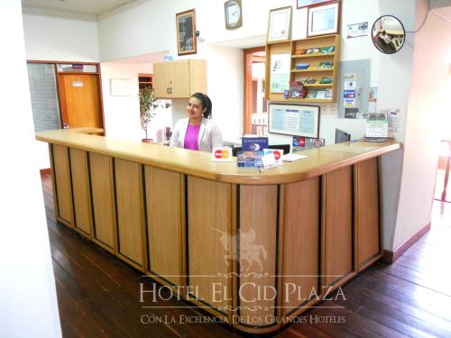 a woman sitting at a counter in a pharmacy at Hotel El Cid Plaza Premium in Tunja