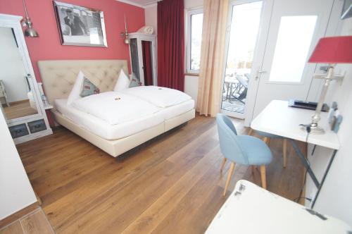 a bedroom with a white bed and a table and a chair at UNO Hotel Chapeau Noir - Free Parking in Überherrn