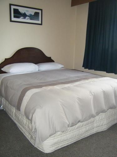 a bed in a bedroom with a large white bedspread at Glendale River View in Manapouri