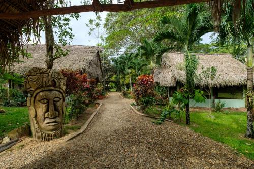 a path leading to a house with a statue of a face at Bocawina Rainforest Resort in Hopkins