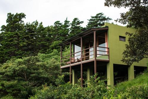 a green house on a hill with trees at Rainbow Valley Lodge Costa Rica in Monteverde Costa Rica