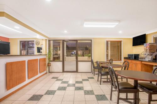 a dining room with tables and chairs and a kitchen at Super 8 by Wyndham Sumter in Sumter