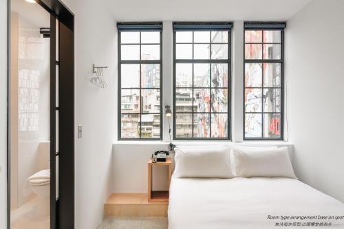 a bedroom with a white bed and windows at Art'otel Ximending Taipei in Taipei