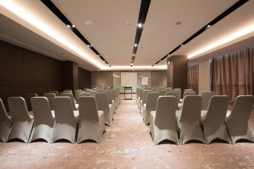 an empty conference room with chairs and a podium at GRAMM HOTEL by Ambarrukmo Yogyakarta in Yogyakarta