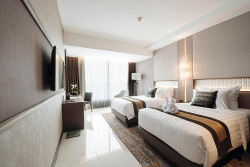 a hotel room with two beds and a television at GRAMM HOTEL by Ambarrukmo Yogyakarta in Yogyakarta